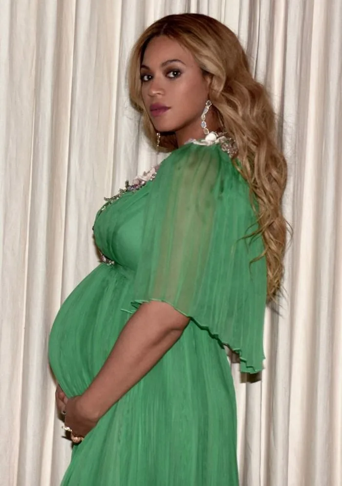 Η Beyoncé σε προφίλ, έγκυος, φορώντας πράσινο φόρεμα.