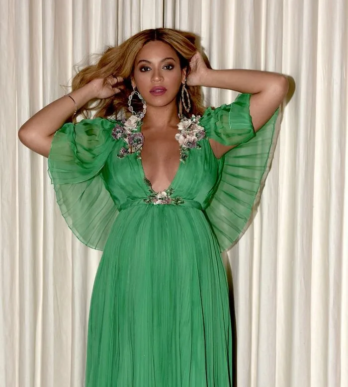 Η Beyoncé με πράσινο πλισέ φόρεμα και λουλουδάτες λεπτομέρειες.