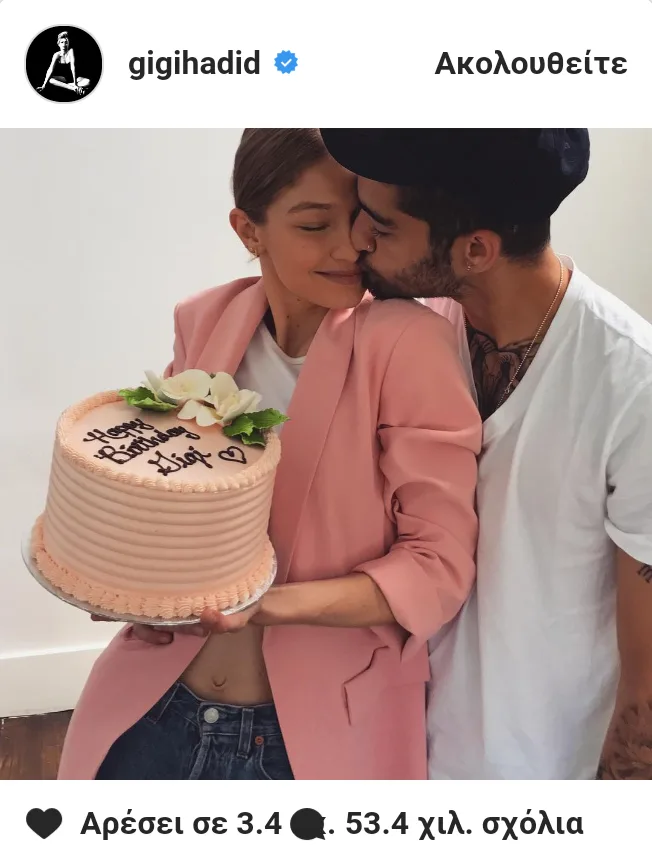 Η Gigi Hadid κρατάει μια ροζ τούρτα γενεθλίων ενώ ο Zayn Malik τη φιλάει στο μάγουλο.