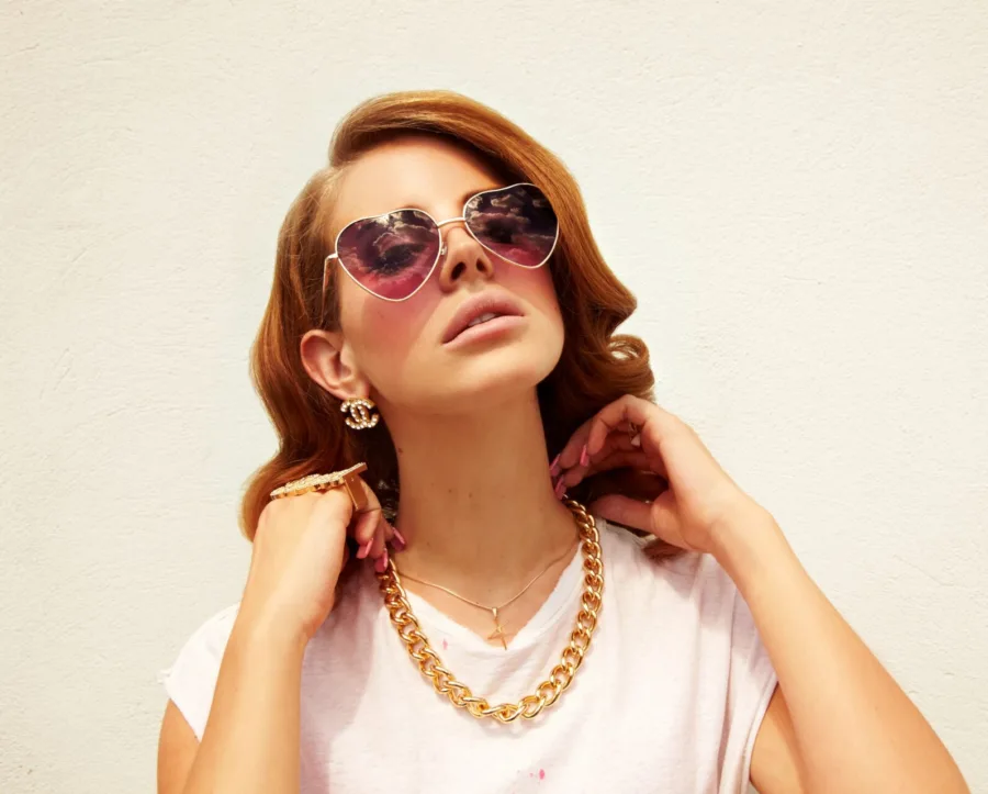 Η Lana Del Rey με γυαλιά ηλίου σε σχήμα καρδιάς και χρυσή αλυσίδα.