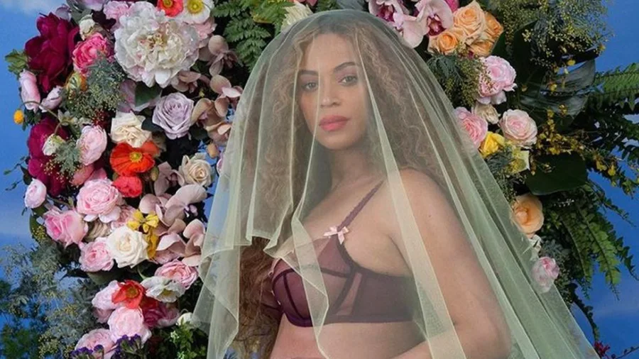 Η Beyoncé ποζάρει με πέπλο μπροστά από μια σύνθεση με λουλούδια.