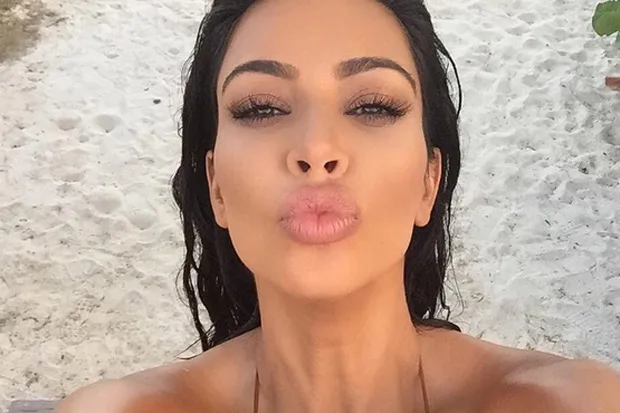 Η Kim Kardashian σε κοντινό πλάνο με φόντο παραλία.