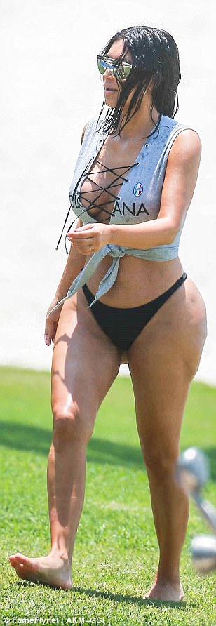 Η Kim Kardashian με γκρι τοπ και μαύρο μαγιό σε εξωτερικό χώρο.