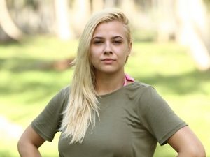 Παίκτρια του Survivor με ξανθά μαλλιά και λαδί μπλούζα.