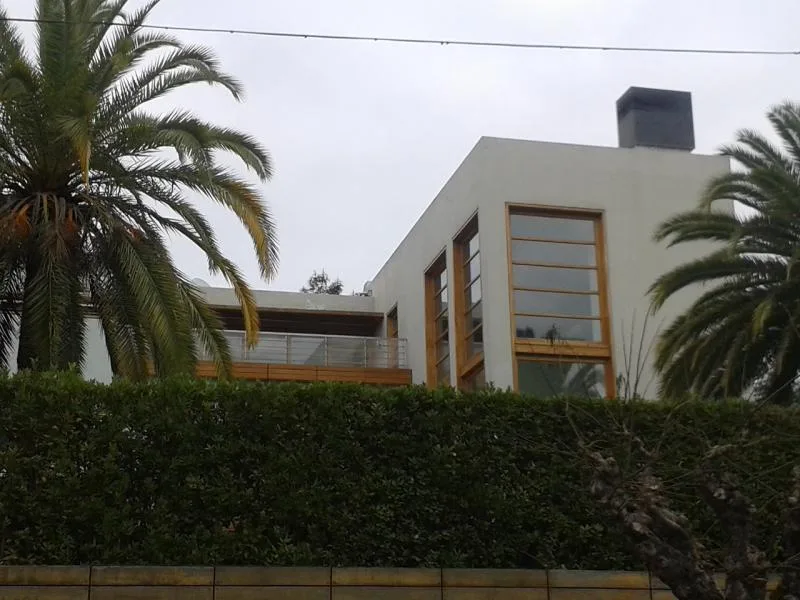 Εξωτερική άποψη μοντέρνας κατοικίας με μεγάλα παράθυρα και φοίνικες.