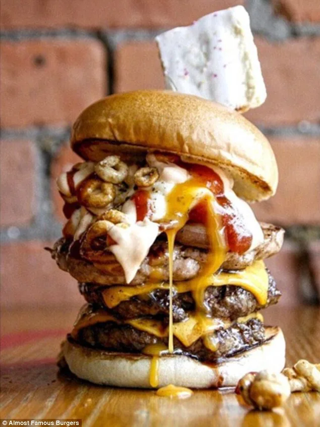Πολυώροφο burger με τρία μπιφτέκια, τυρί, σάλτσες, δημητριακά και ένα γλυκό στην κορυφή.