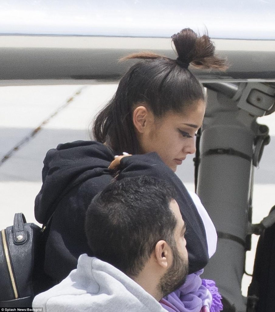 Η Ariana Grande κατεβαίνει από αεροπλάνο με σκυμμένο κεφάλι.