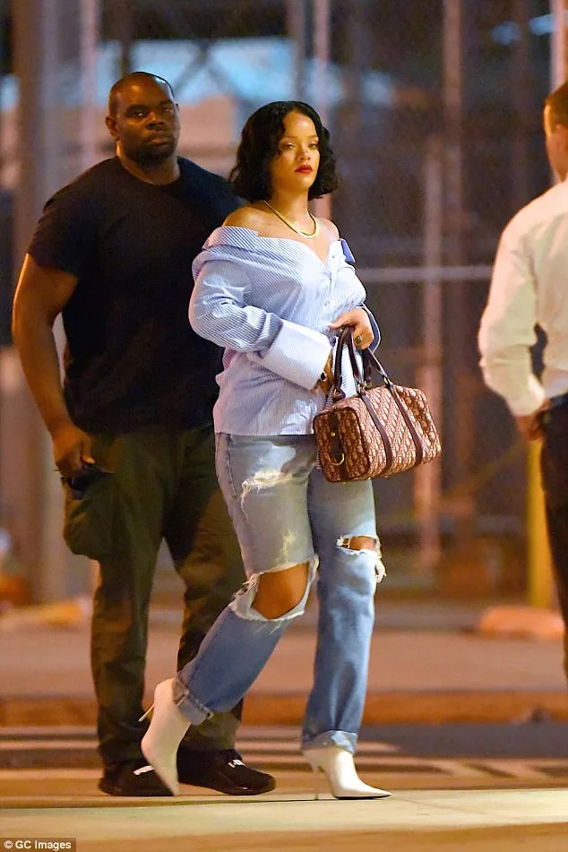 Η Rihanna περπατά στο δρόμο φορώντας ριγέ πουκάμισο και σκισμένο τζιν.