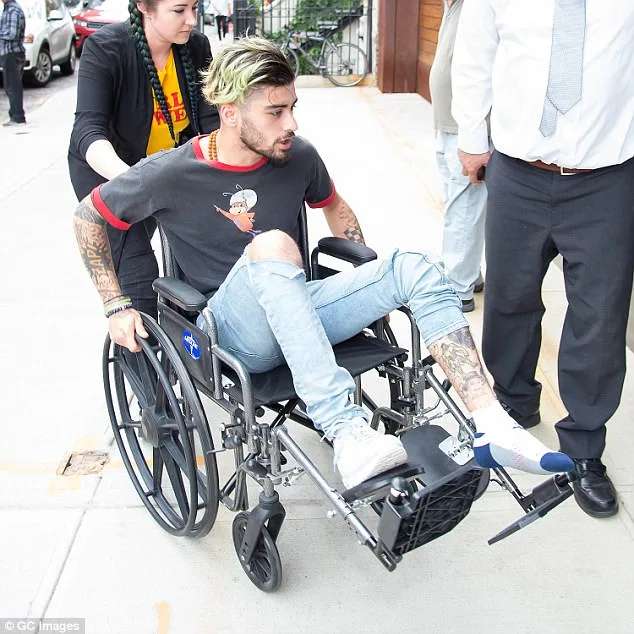 Ο Zayn Malik σε αναπηρικό καροτσάκι έξω από κτίριο.