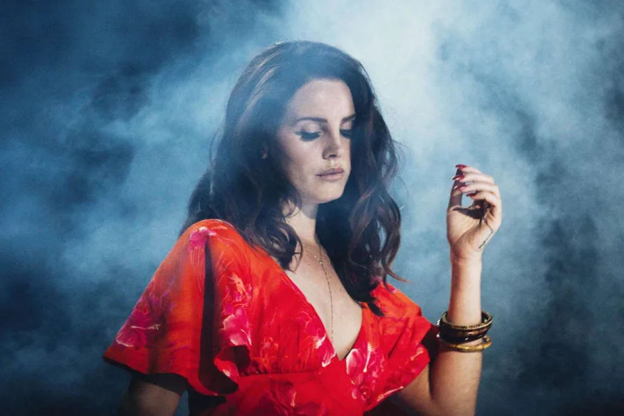 Η Lana Del Rey με κόκκινο φλοράλ φόρεμα μέσα σε καπνό.