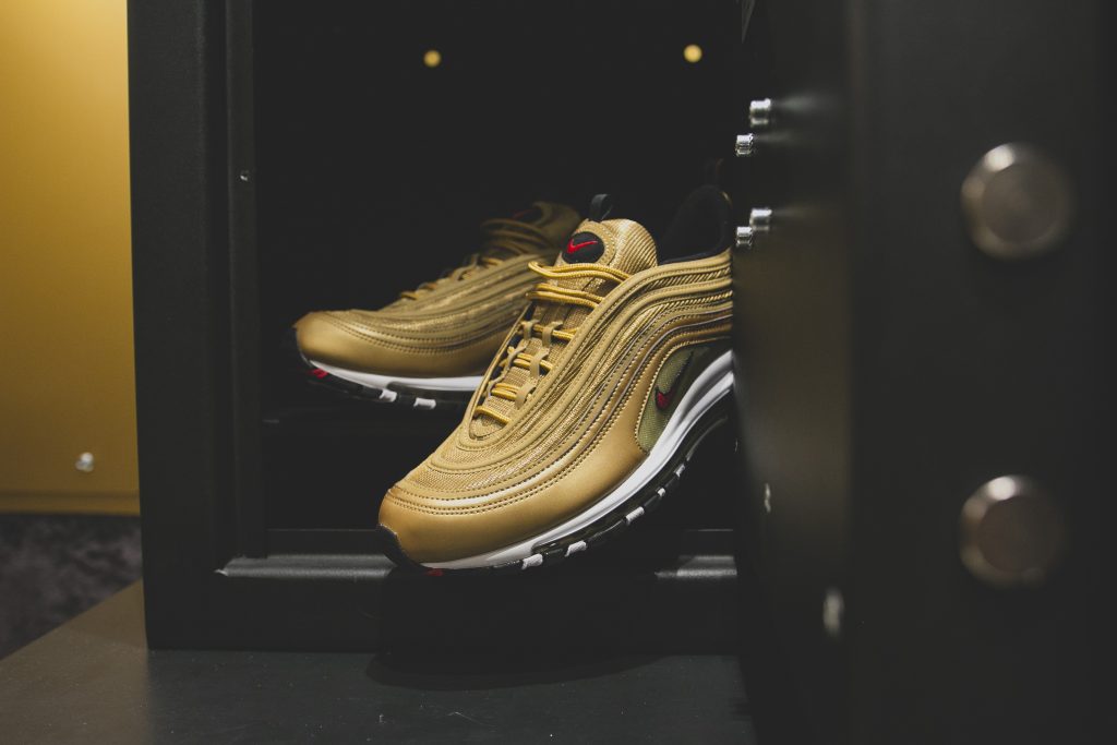 Ένα ζευγάρι χρυσά αθλητικά παπούτσια Nike Air Max 97 Metallic Gold μέσα σε χρηματοκιβώτιο.