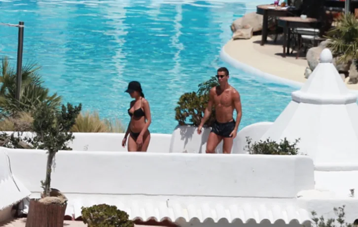 Ο Cristiano Ronaldo και η Georgina Rodriguez με μαγιό δίπλα σε πισίνα.