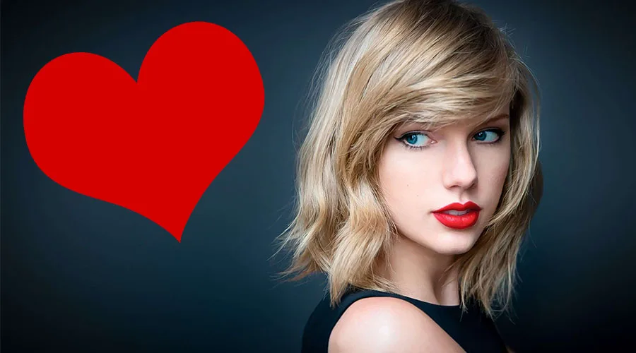 Η Taylor Swift με ξανθό καρέ μαλλί και κόκκινο κραγιόν δίπλα σε μια μεγάλη κόκκινη καρδιά.