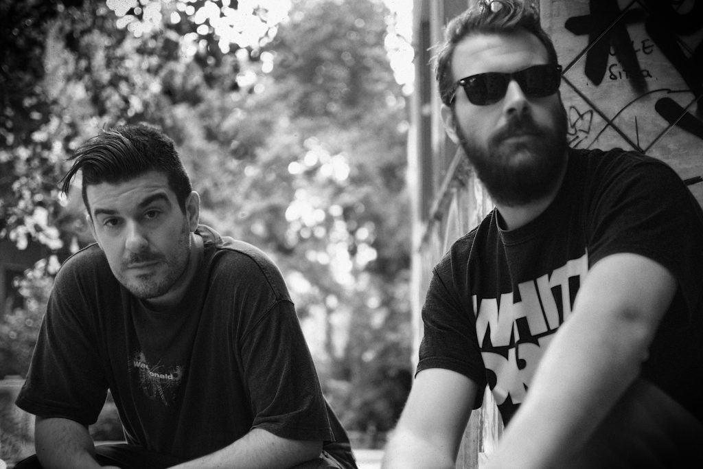 Δύο άνδρες καλλιτέχνες σε ασπρόμαυρη φωτογραφία σε εξωτερικό χώρο.