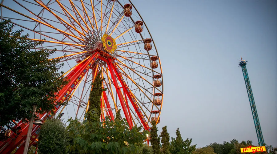 Μεγάλη ρόδα και πύργος πτώσης στο Allou! Fun Park κατά το σούρουπο.