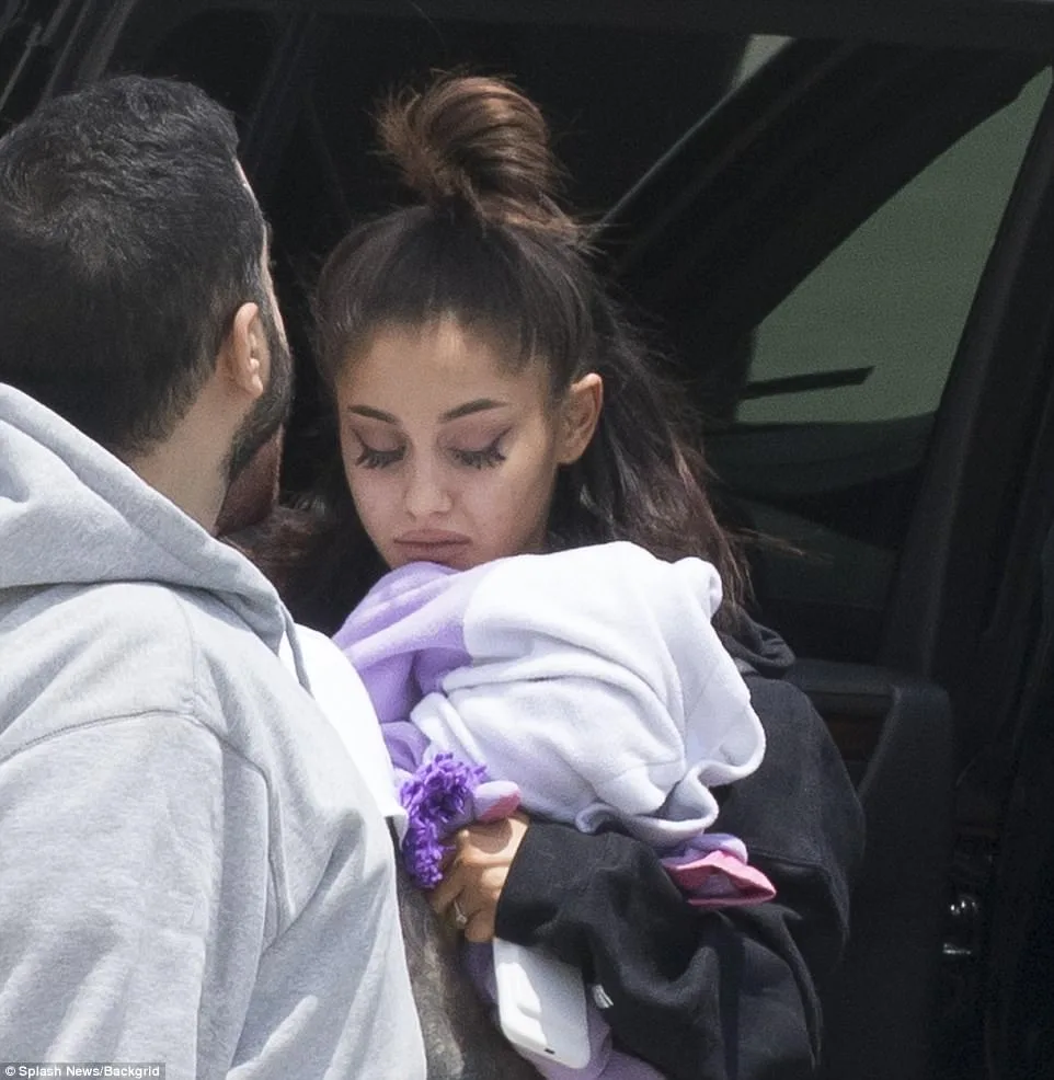 Η Ariana Grande με σκυμμένο κεφάλι κρατώντας μια κουβέρτα.