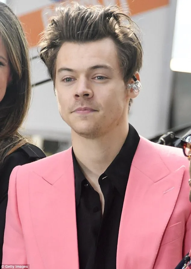 Ο Harry Styles με ροζ κοστούμι και μαύρο πουκάμισο.