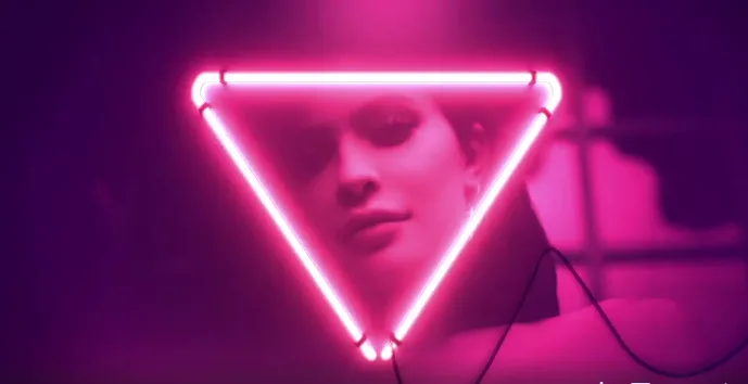 Η Kylie Jenner μέσα σε ένα φωτεινό ροζ νέον τρίγωνο.
