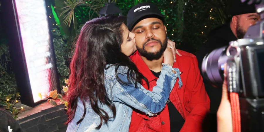 Η Selena Gomez φιλάει τον The Weeknd στο μάγουλο.