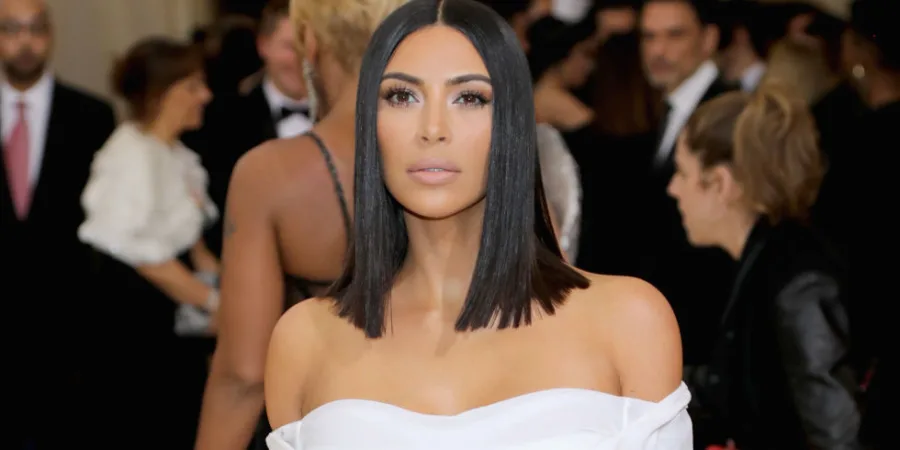 Η Kim Kardashian με μαύρο καρέ μαλλί και λευκό εξώπλατο φόρεμα σε κοσμική εκδήλωση.