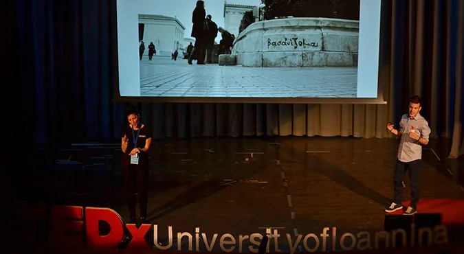 Ομιλητής σε σκηνή TEDxUniversityofIoannina με προβολή φωτογραφίας.