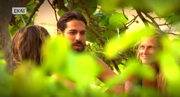 Παίκτες του Survivor συνομιλούν ανάμεσα σε φυλλωσιές.