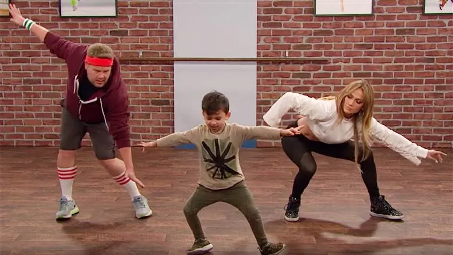 Η Jennifer Lopez και ο James Corden χορεύουν με ένα μικρό παιδί σε στούντιο.