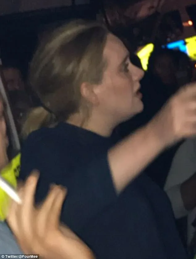Η Adele σε νυχτερινή λήψη με σκούρο ρούχο και πιασμένα μαλλιά.