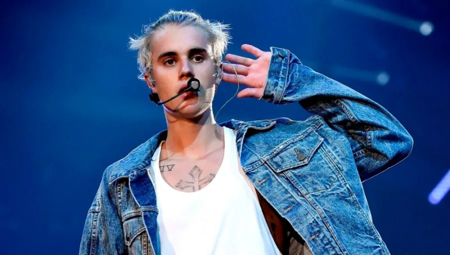 Ο Justin Bieber στη σκηνή με τζιν τζάκετ και μικρόφωνο κεφαλής.