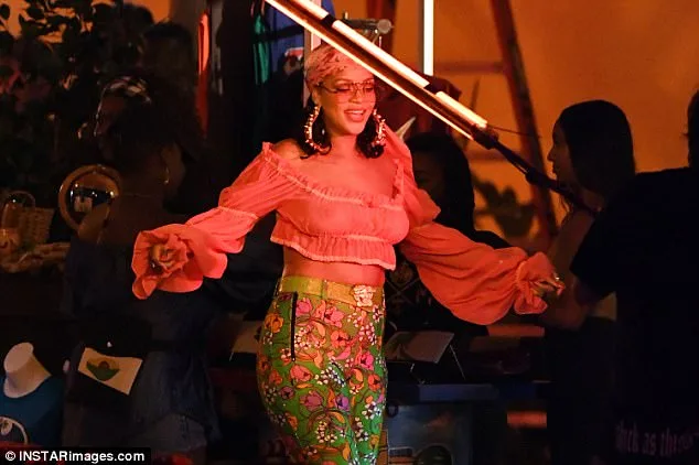 Η Rihanna με ημιδιαφανές πορτοκαλί crop top και φλοράλ παντελόνι.
