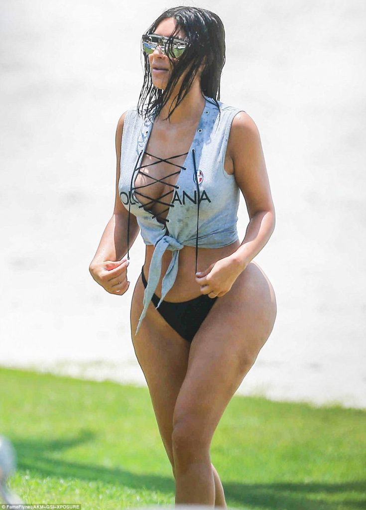Η Kim Kardashian με γκρι δετό τοπ και μαύρο μαγιό στην παραλία.
