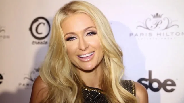 Η Paris Hilton χαμογελά σε εκδήλωση με ξανθά μαλλιά.
