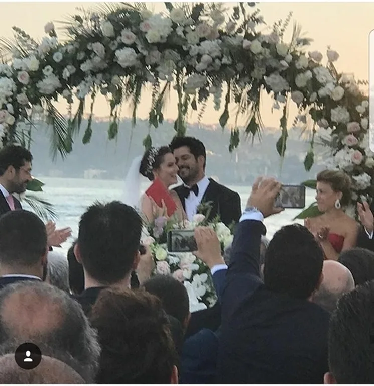 Ο Burak Ozcivit και η Fahriye Evcen στον γάμο τους κάτω από μια ανθοστόλιστη αψίδα.