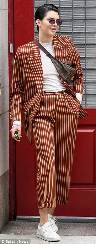 Η Kendall Jenner με ριγέ κοστούμι και fidget spinner στο χέρι.