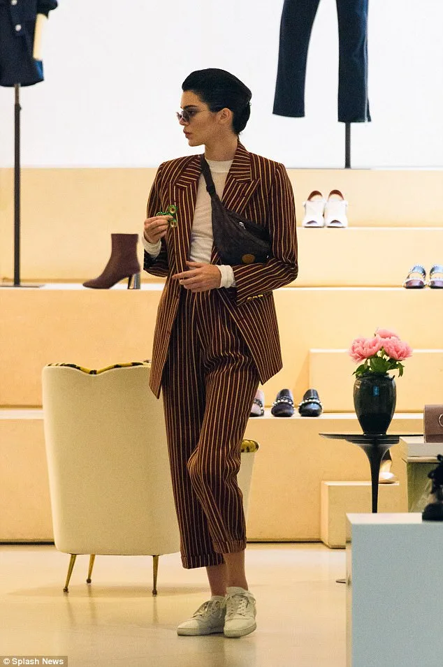 Η Kendall Jenner με ριγέ κοστούμι κρατώντας ένα fidget spinner.