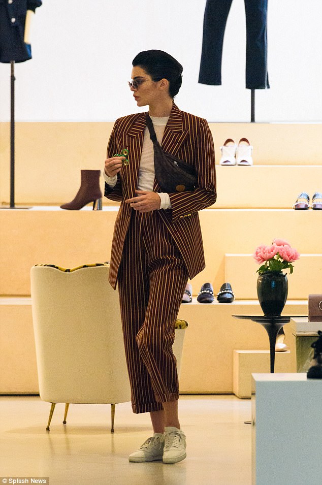 Η Kendall Jenner με ριγέ κοστούμι κρατώντας ένα fidget spinner.