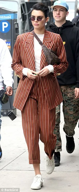 Η Kendall Jenner με ριγέ κοστούμι και fidget spinner στο χέρι.