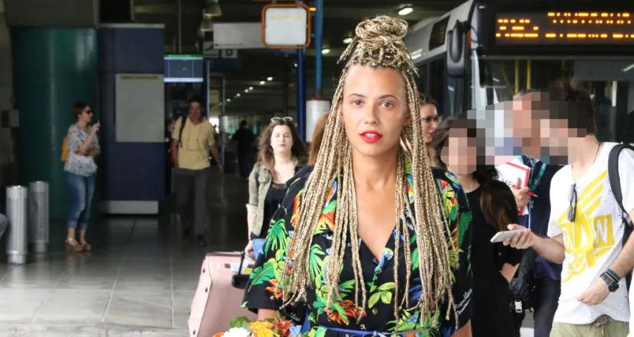 Η Λάουρα Νάργες με ξανθά ράστα κοτσιδάκια σε αεροδρόμιο.