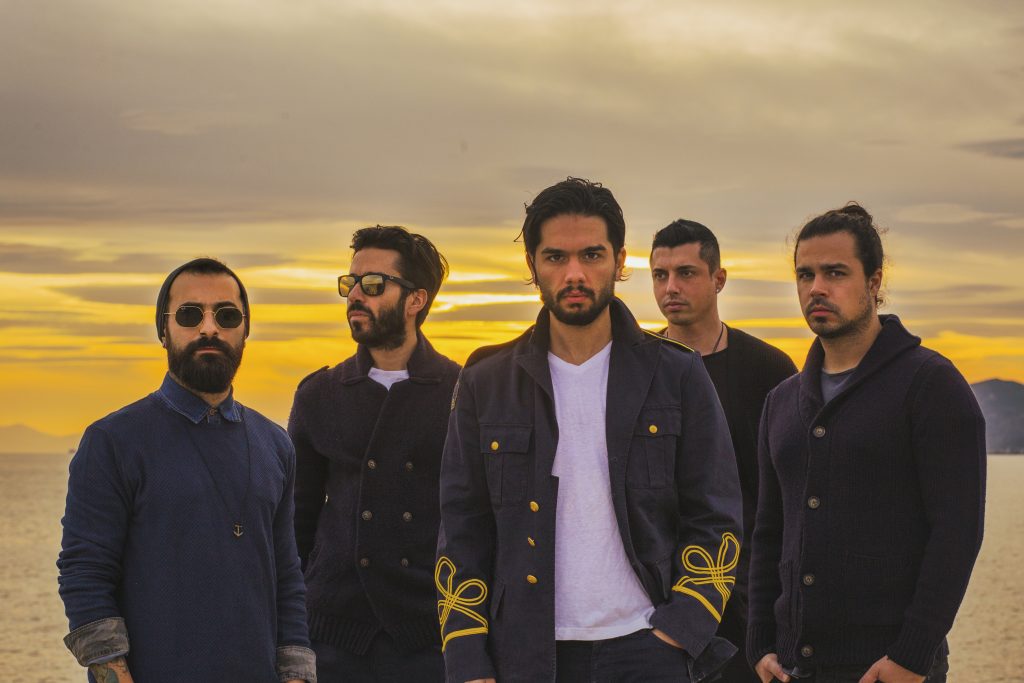 Ελληνικό pop-rock συγκρότημα σε εξωτερικό χώρο κατά τη διάρκεια του ηλιοβασιλέματος.