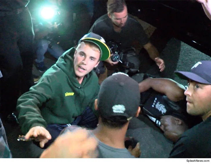 Ο Justin Bieber σκυμμένος πάνω από τραυματισμένο φωτογράφο στο έδαφος.