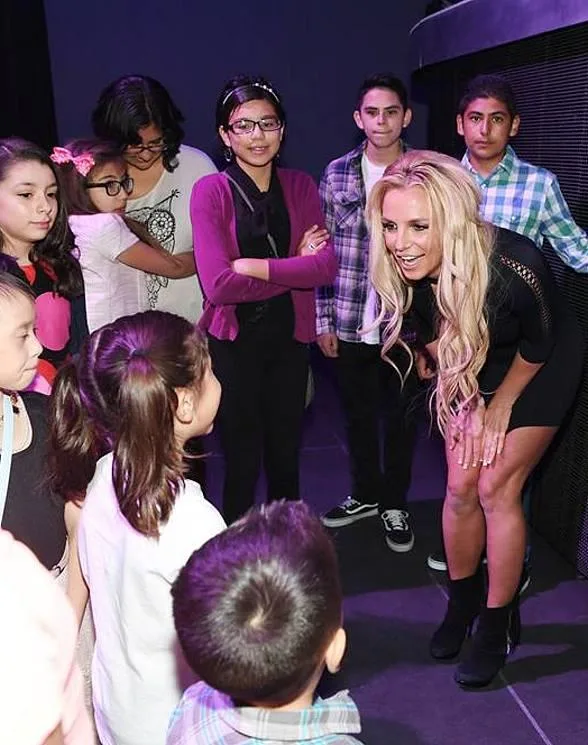 Η Britney Spears χαμογελά και μιλάει σε μια ομάδα παιδιών.