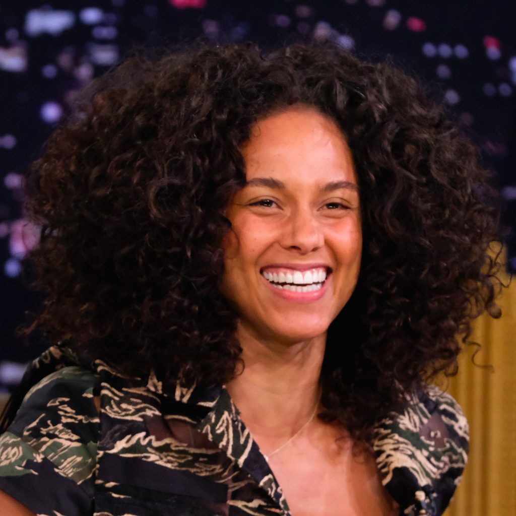 Η Alicia Keys χαμογελάει με πλούσια σγουρά μαλλιά.