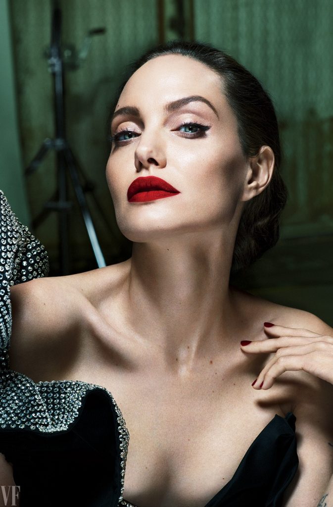 Κοντινό πορτρέτο της Angelina Jolie με κόκκινο κραγιόν και μαύρο φόρεμα με στρας.