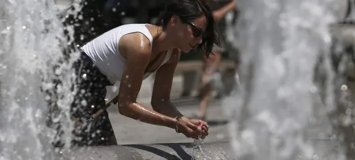Γυναίκα δροσίζεται σε σιντριβάνι κατά τη διάρκεια καύσωνα.
