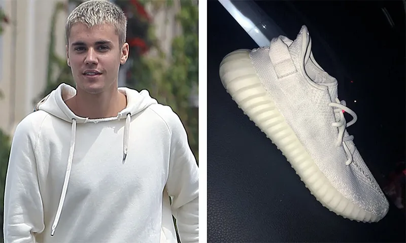 Ο Justin Bieber με λευκό φούτερ και ένα αθλητικό παπούτσι Adidas Yeezy Boost 350 V2.
