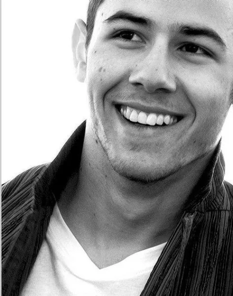 Κοντινό ασπρόμαυρο πορτρέτο του Nick Jonas να χαμογελά.