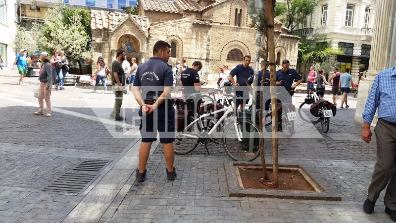 Αστυνομικοί με ποδήλατα στο κέντρο της Αθήνας μπροστά από βυζαντινό ναό.