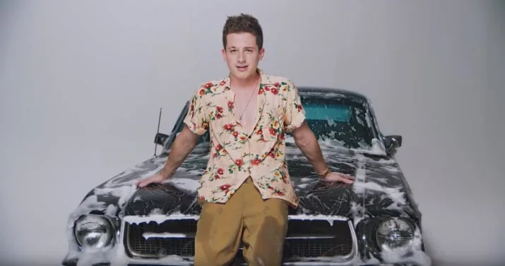 Ο Charlie Puth ποζάρει πάνω σε ένα αυτοκίνητο καλυμμένο με σαπουνάδες.