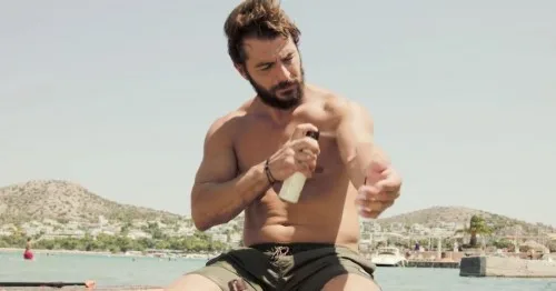 Ο Γιώργος Αγγελόπουλος (Ντάνος) βάζει αντηλιακό σε παραλία.