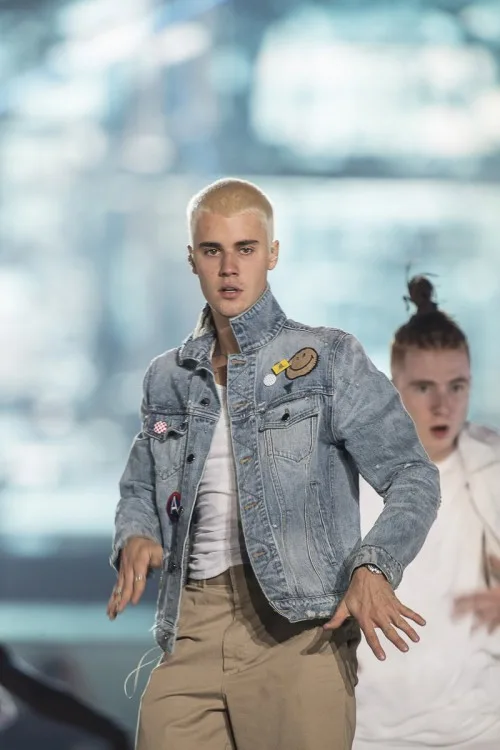 Ο Justin Bieber με ξανθό μαλλί, τζιν μπουφάν και μπεζ παντελόνι στη σκηνή.